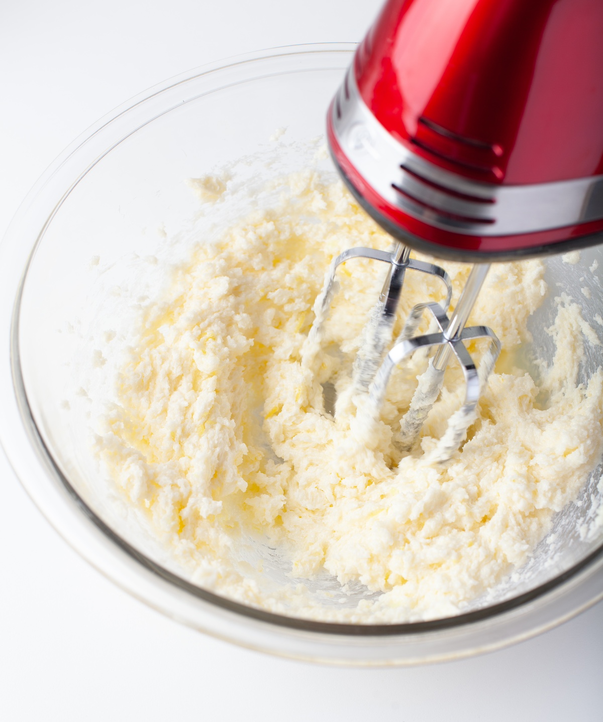 Creaming together butter and sugar in a glass bowl with a red mixer