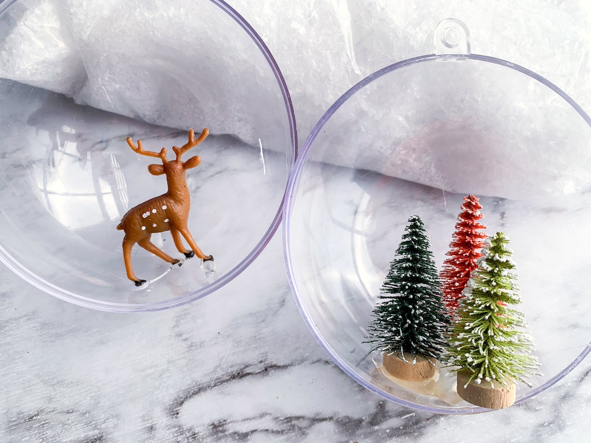 Plastic deer and bottle brush trees glued inside the ornament halves