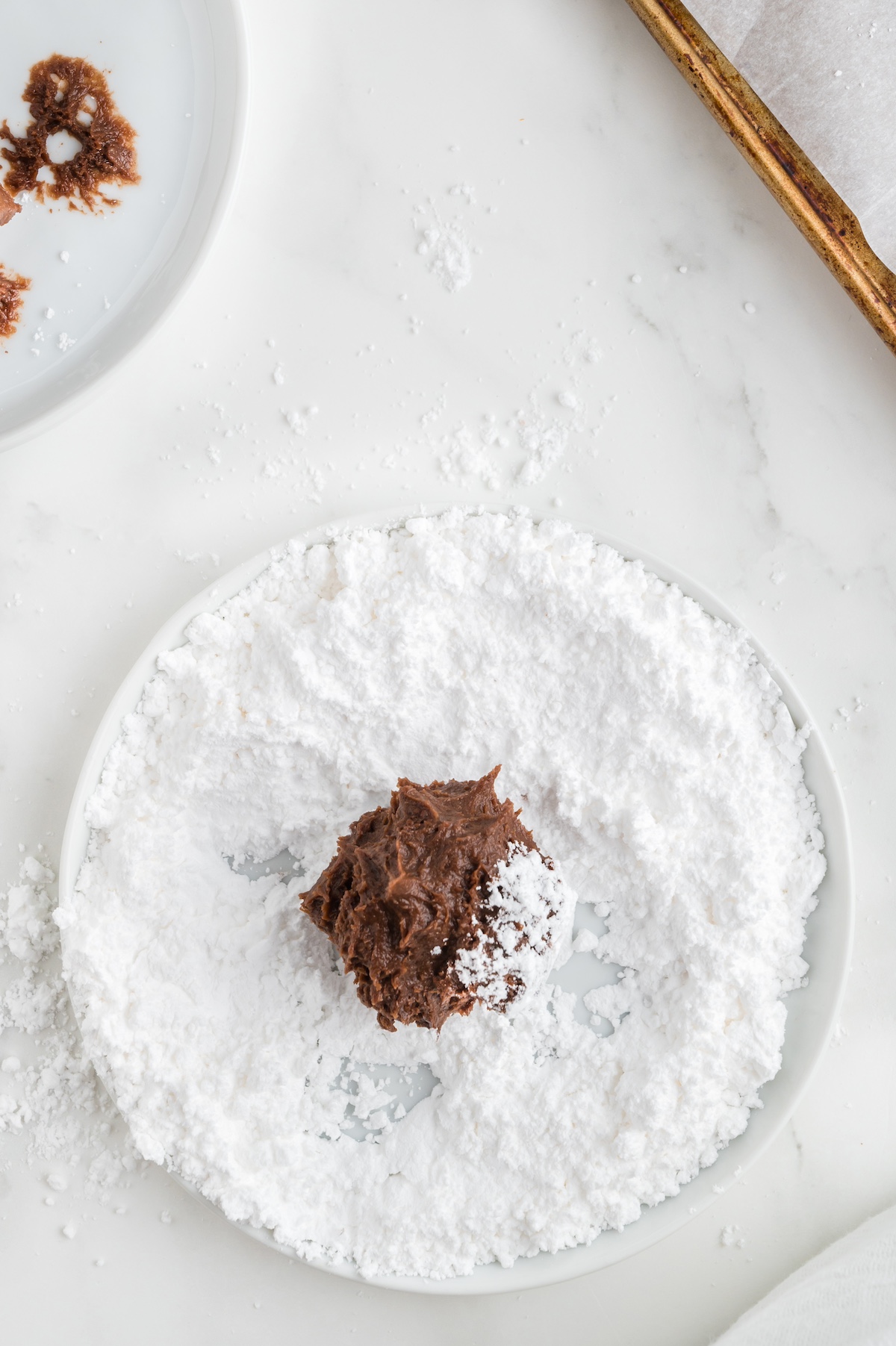rolling chocolate dough balls in powdered sugar