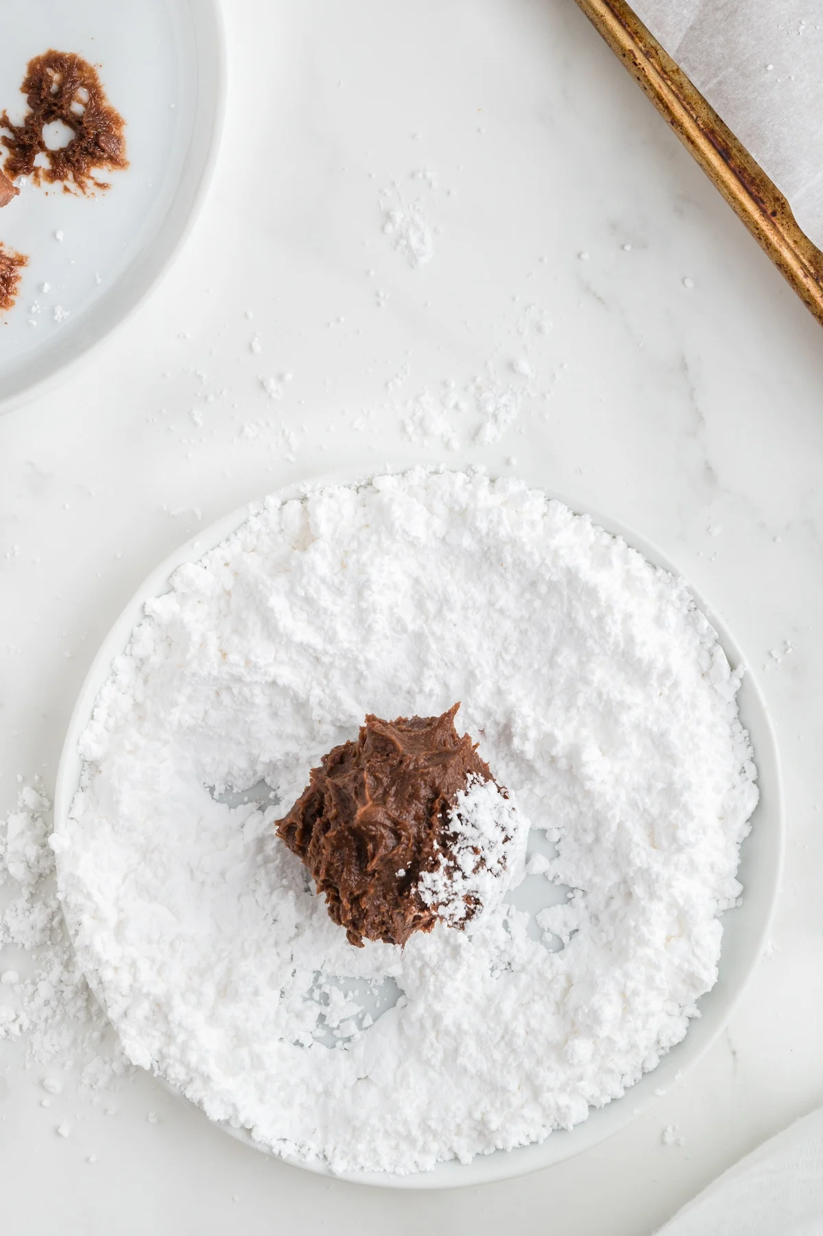 rolling chocolate dough balls in powdered sugar