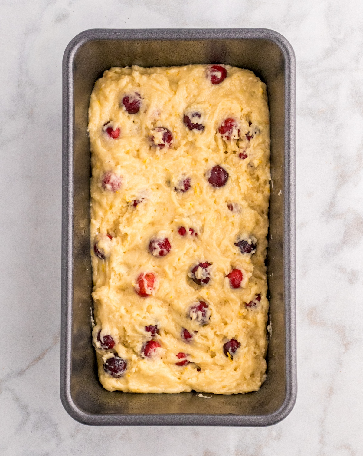 Added batter to a loaf pan with cranberries sprinkled on top