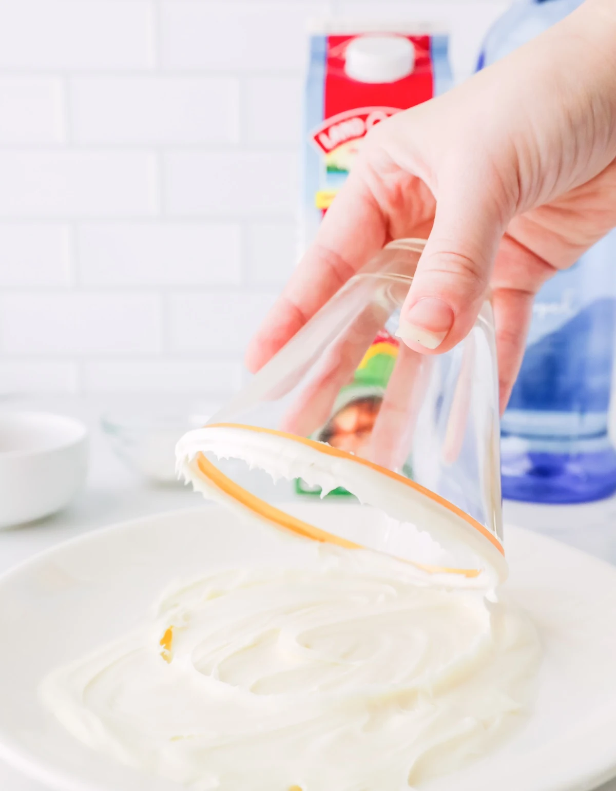 Dipping a glass into vanilla frosting