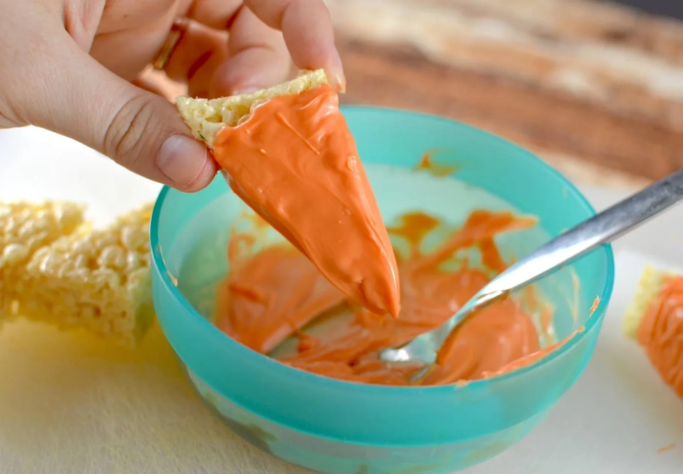 Dipping a rice krispie into orange candy melts