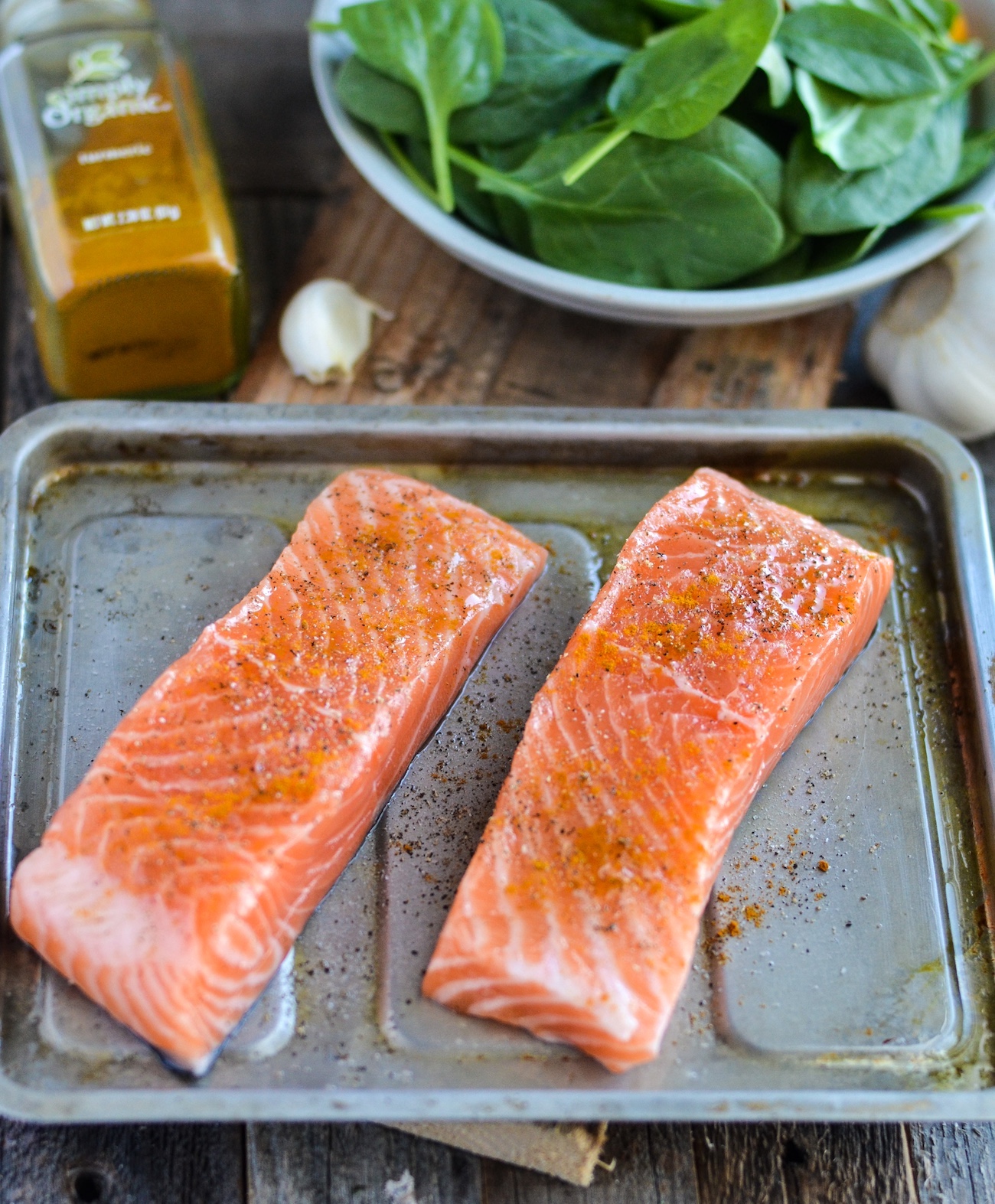 Two raw pieces of salmon seasoned on a baking pan