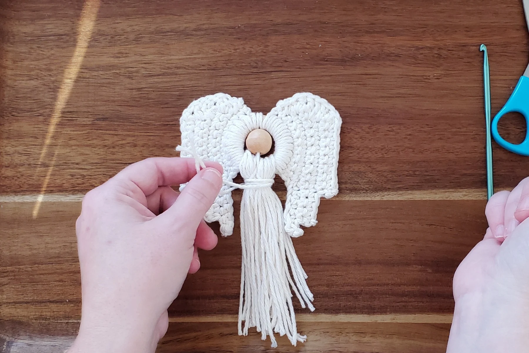 Wrap the two yarn tails around both bunches to form a waist on your crochet angel ornament.