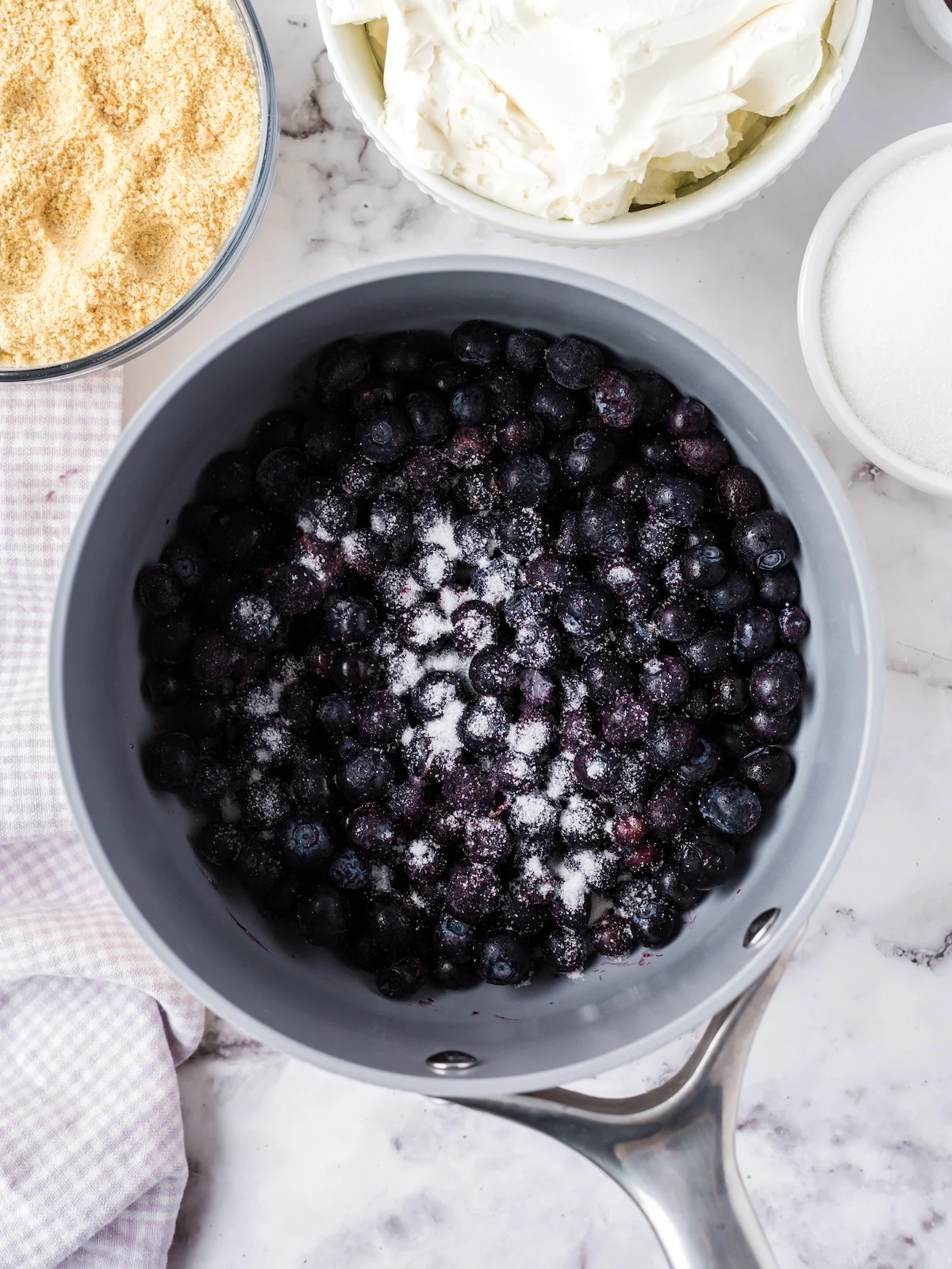 blueberries and sugar added to a saucepan