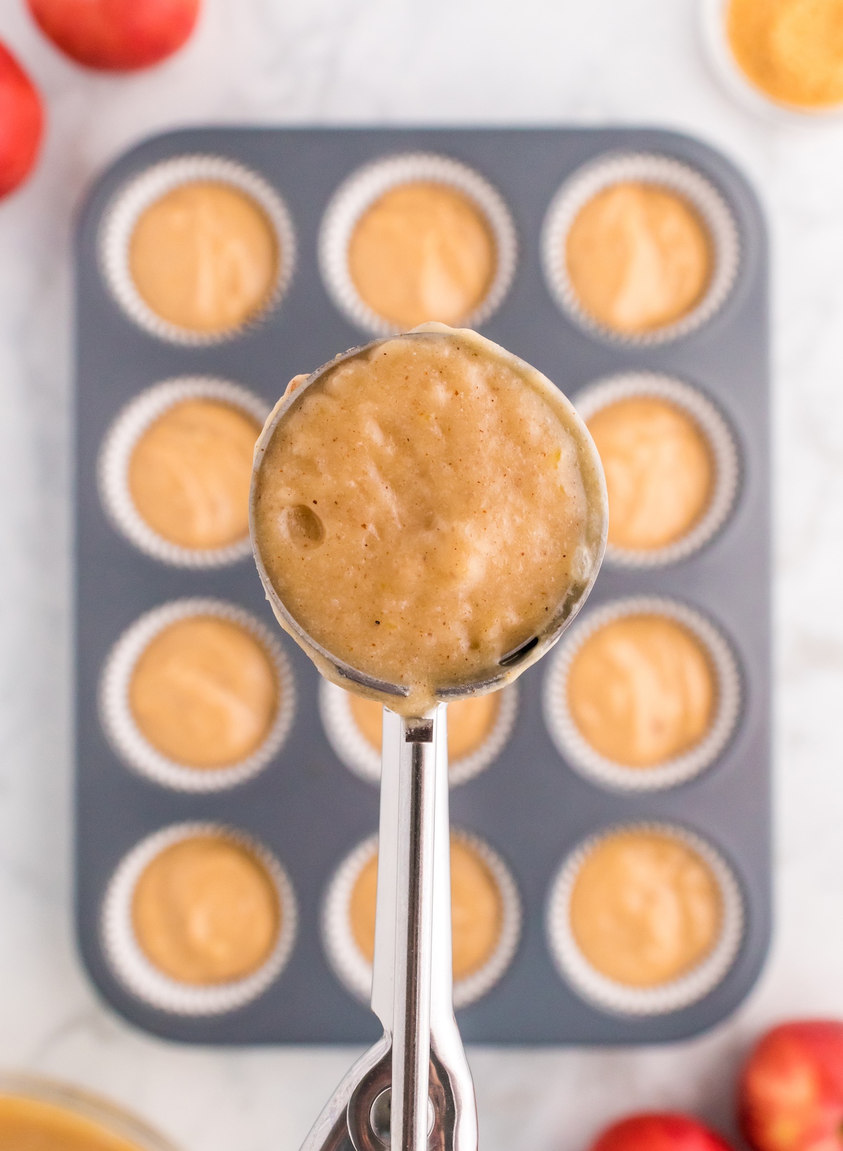 spooning the apple cider batter into the muffin tin