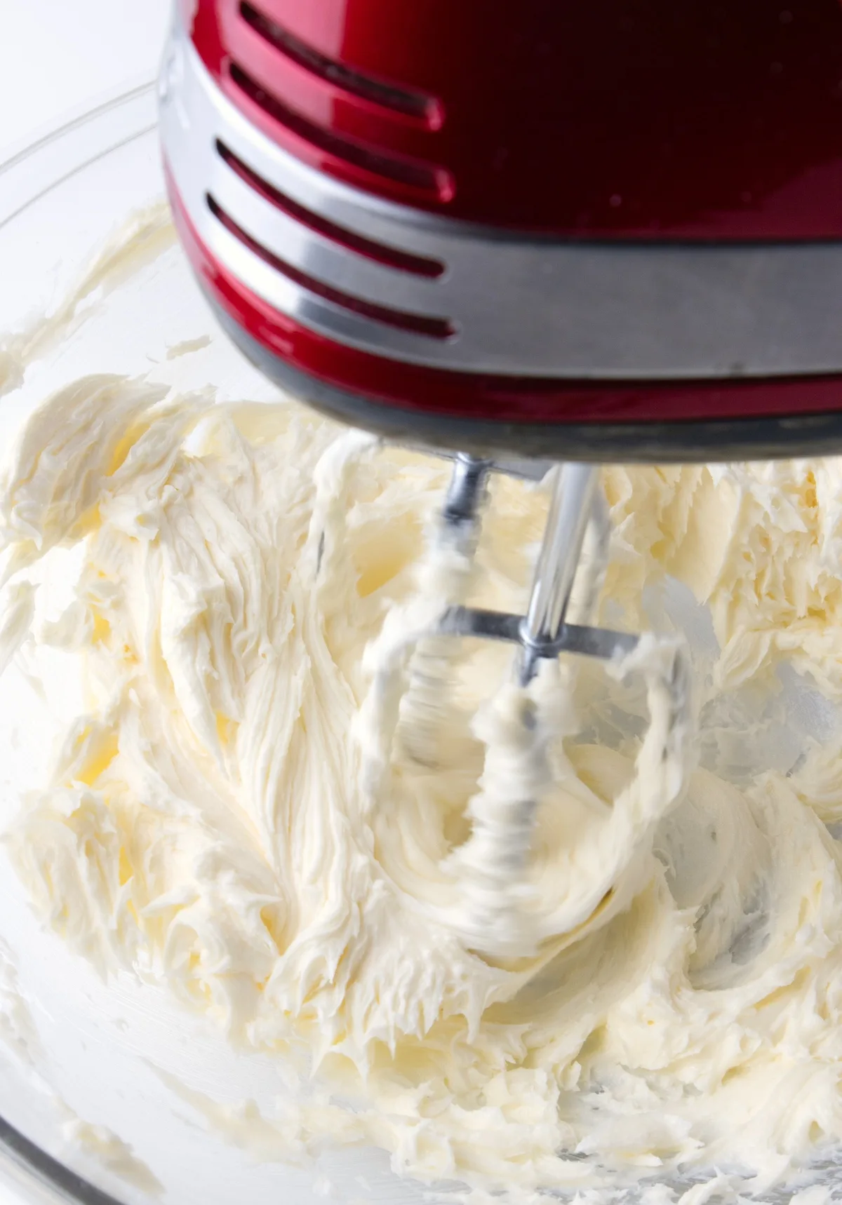 Creaming together butter and sugar with a red mixer in a glass bowl