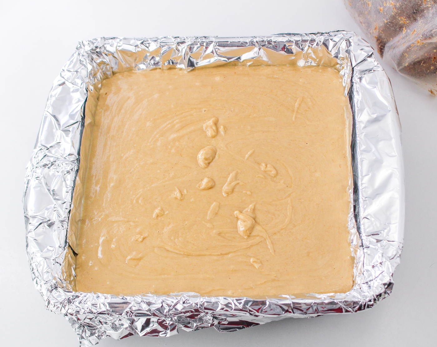 Pouring peanut butter fudge into a lined pan