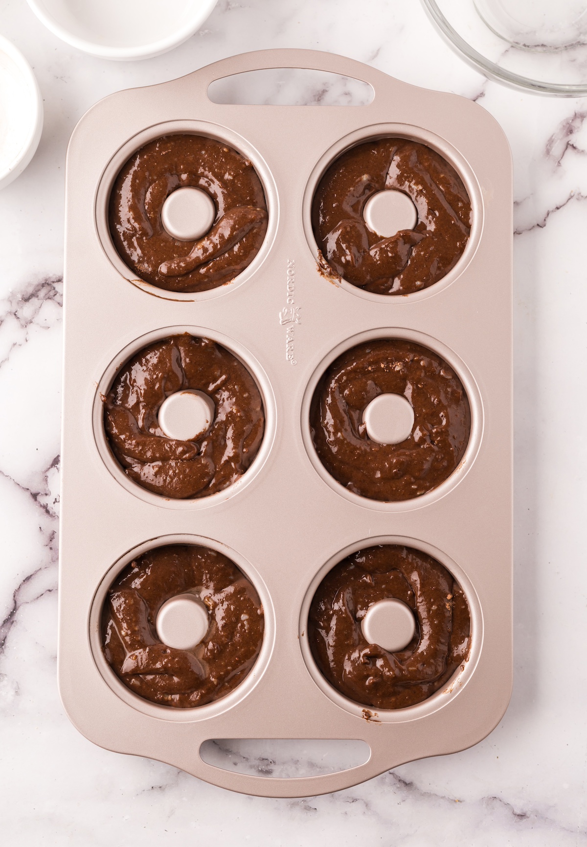 Chocolate donut batter added to a donut pan