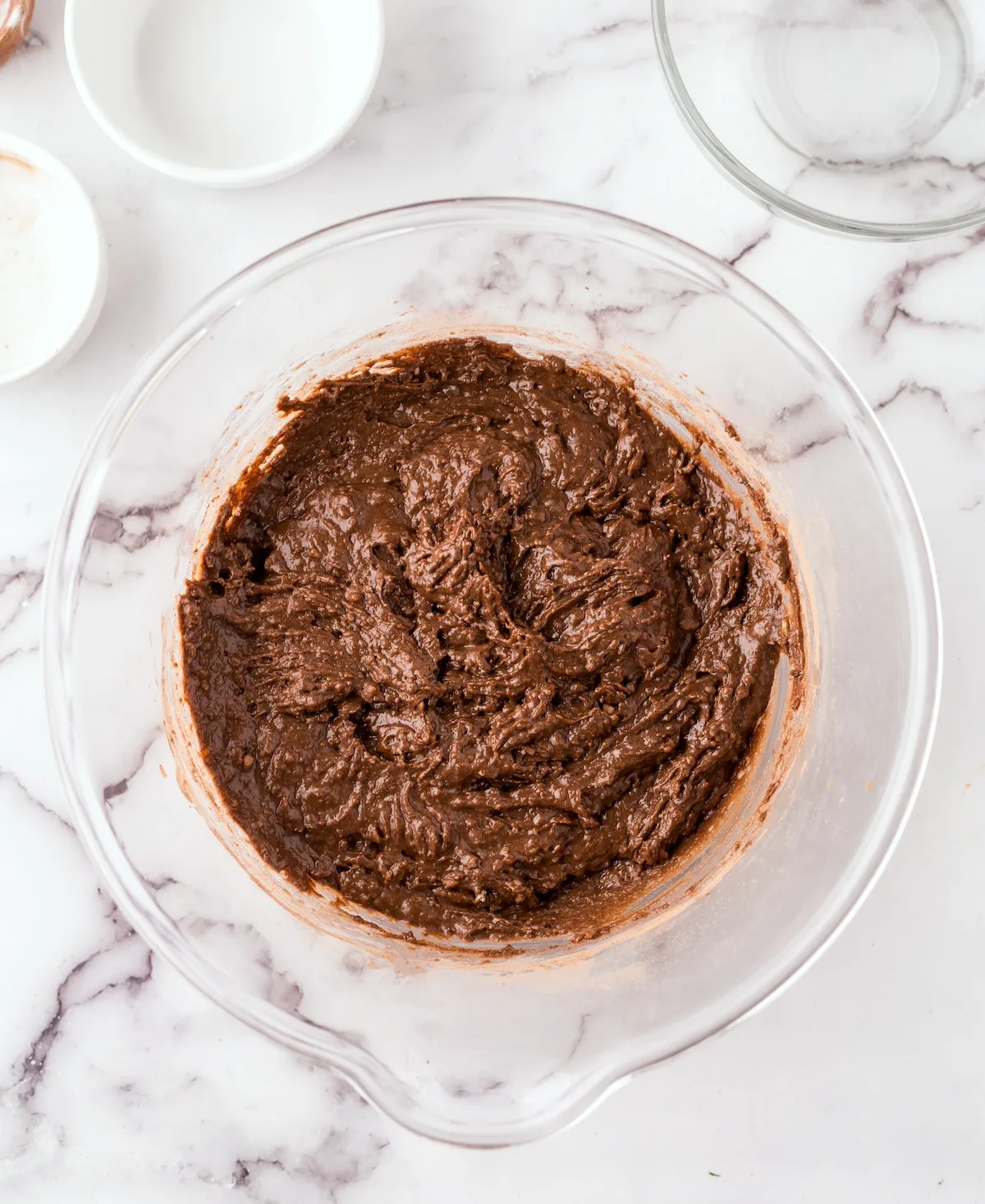 Flour, cocoa powder, sugar, and baking soda mixed with the wet ingredients in the bowl