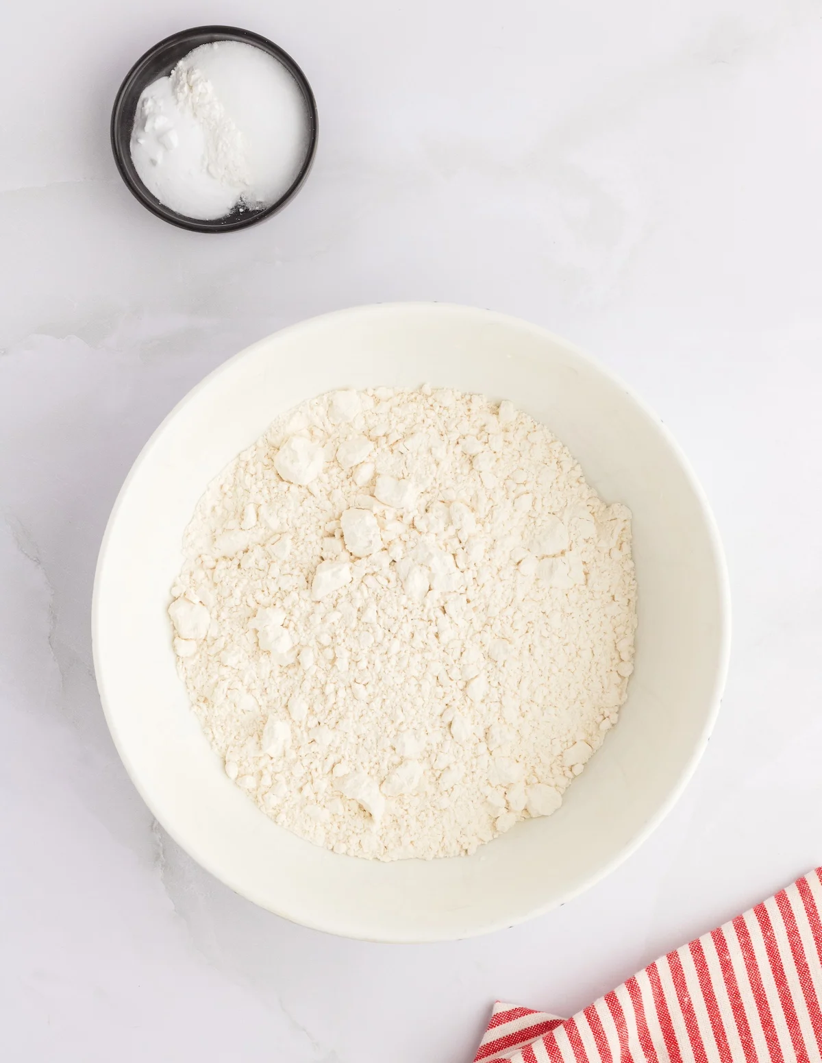 Flour in a large white bowl mixed with baking powder and salt