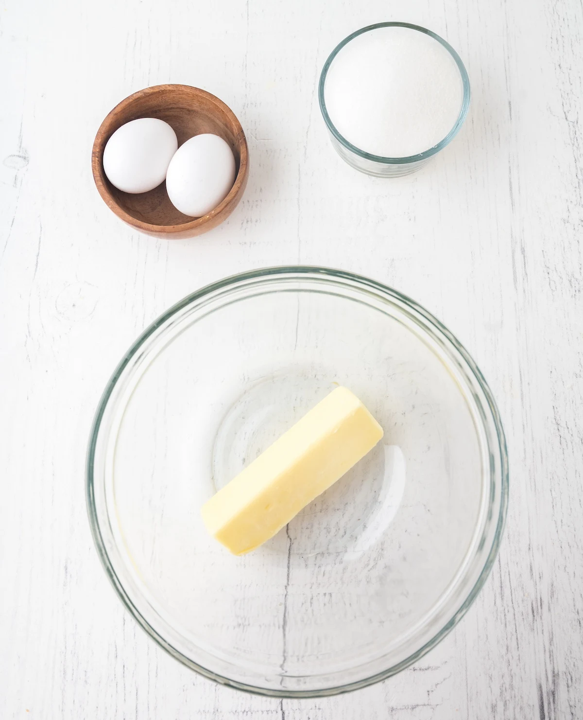 Butter in a clear glass bowl with eggs and sugar