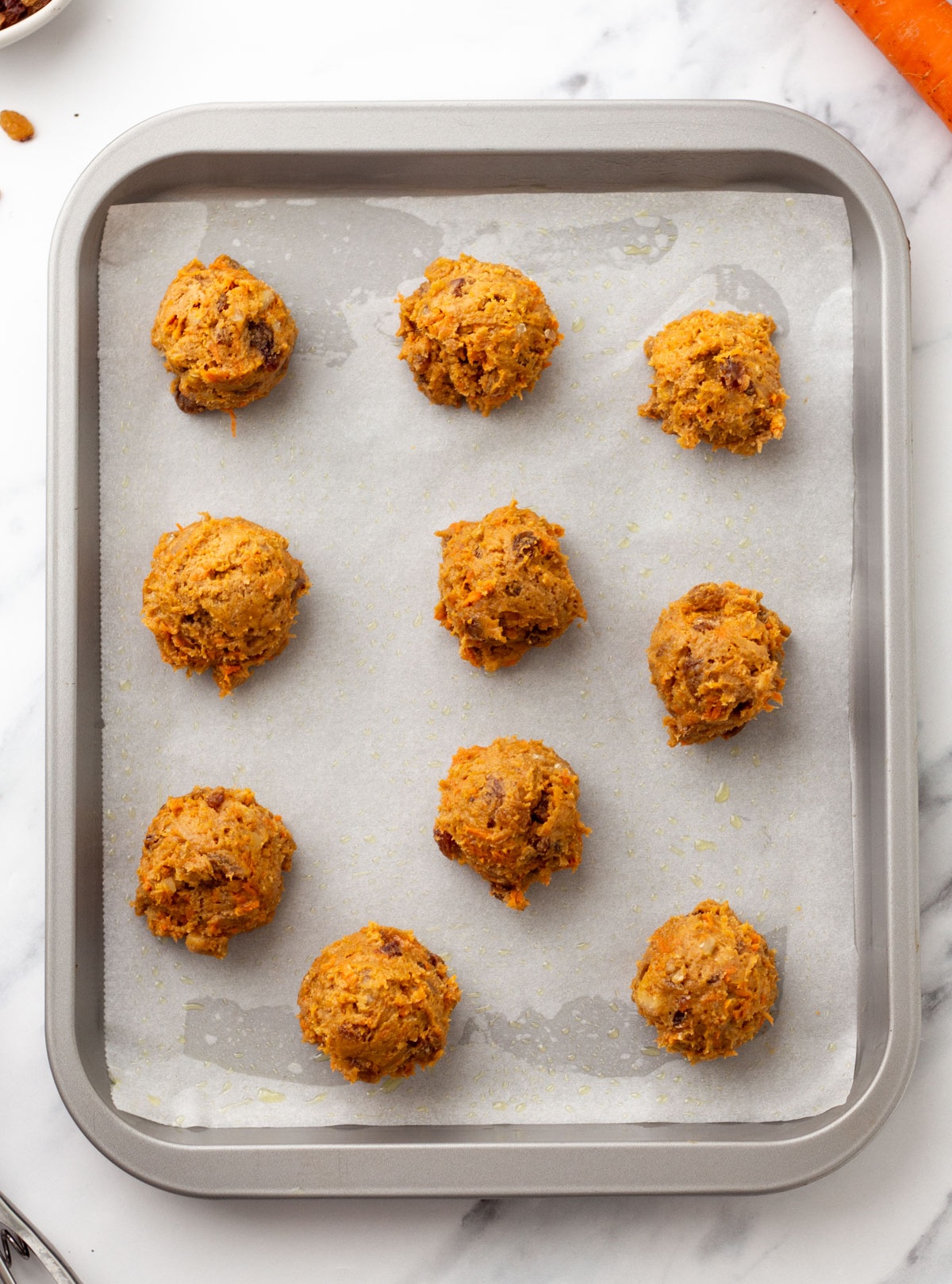 Carrot cookie dough added to the baking sheet