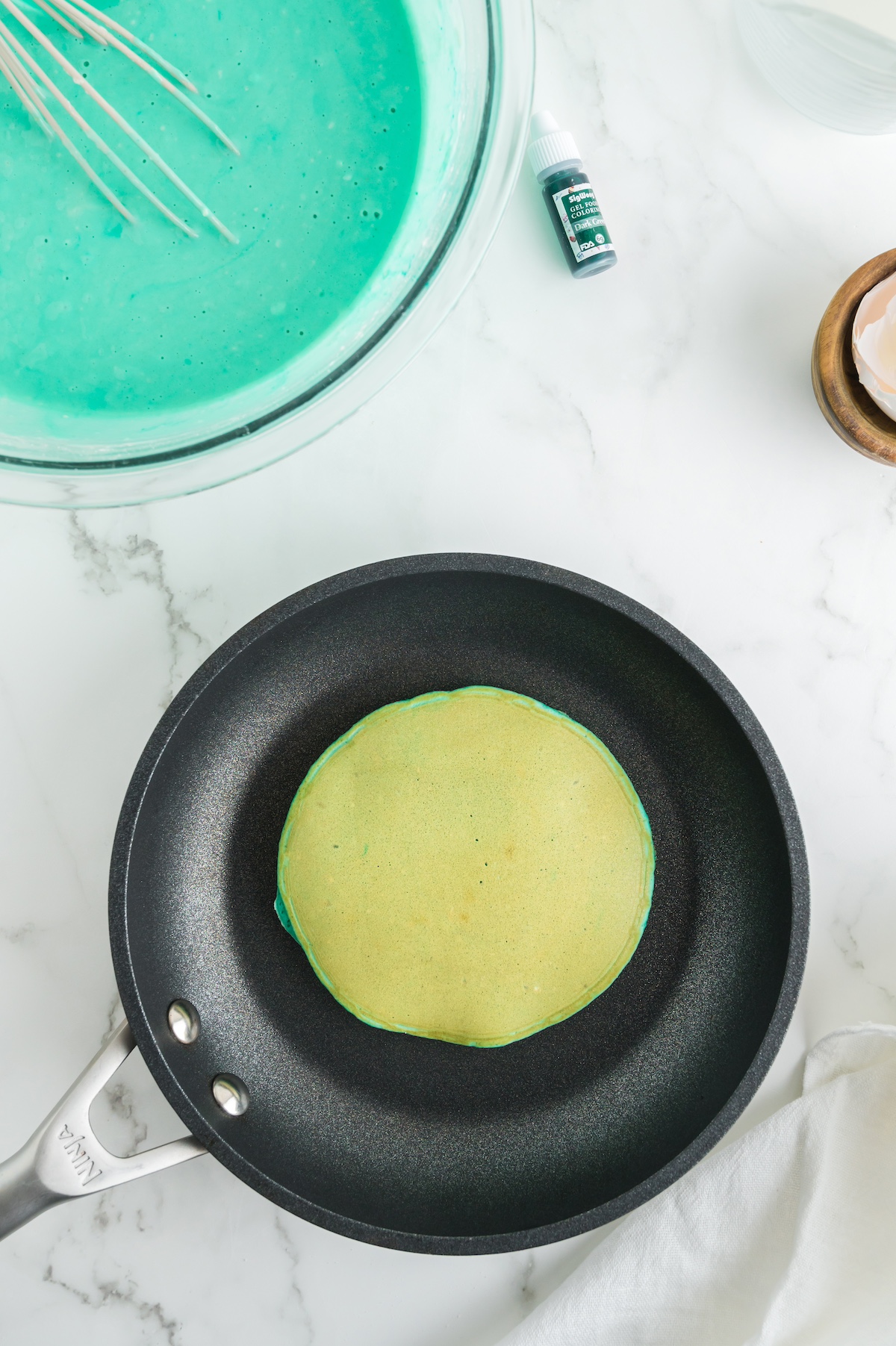 Green pancake flipped over in a pan