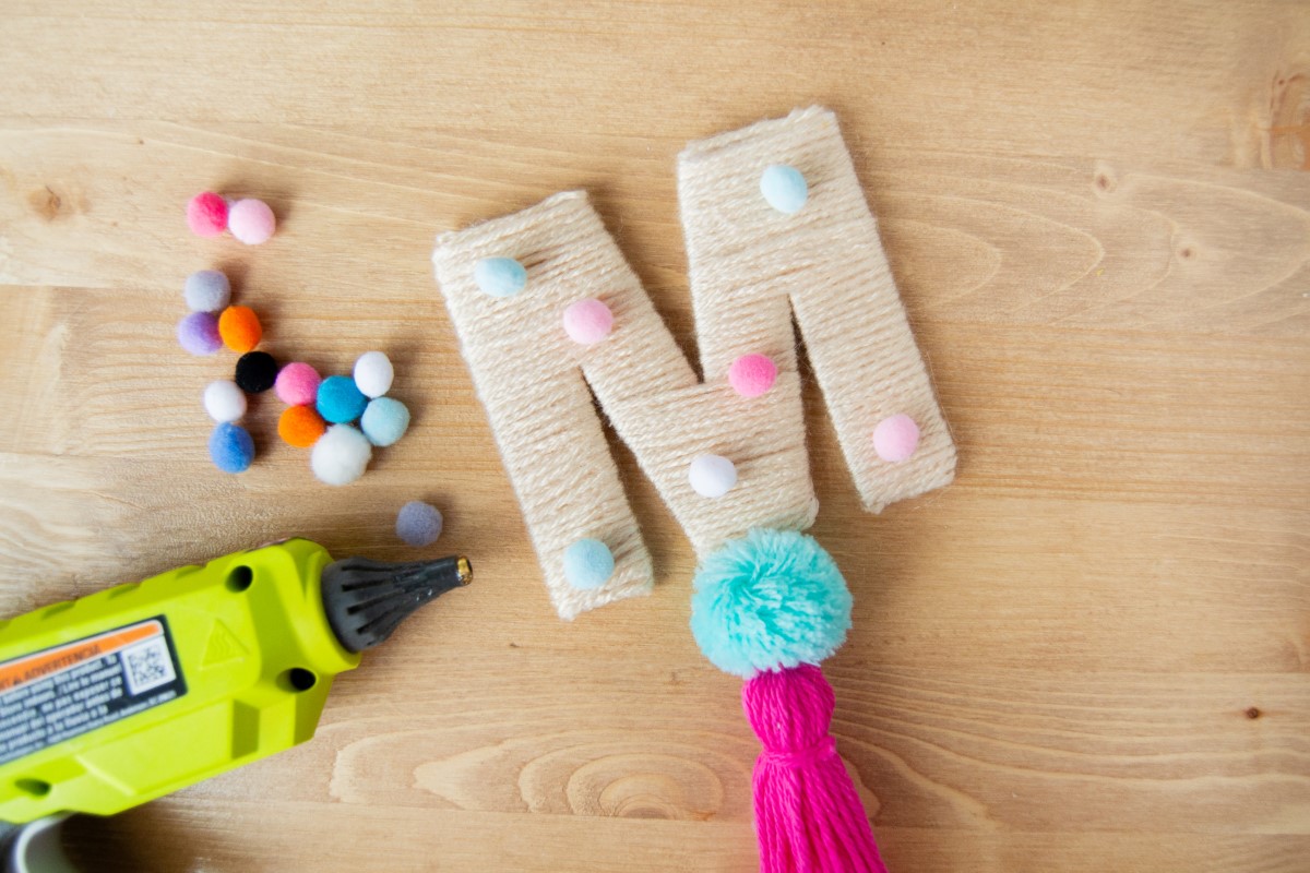 Hot glue mini pom poms to the front of the letter