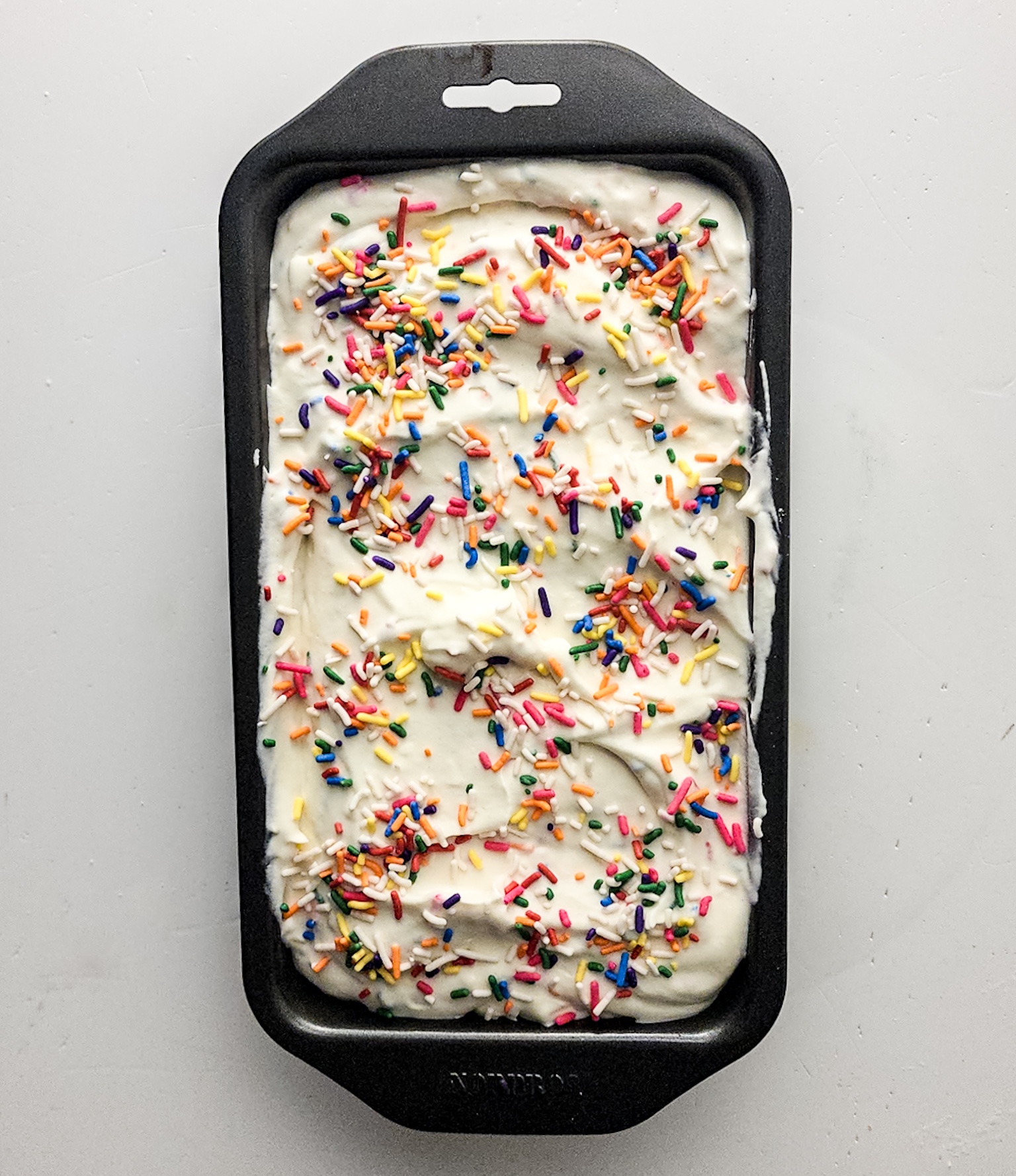 Ice cream added to a metal pan and topped with sprinkles