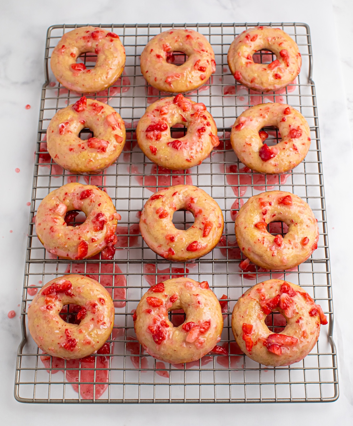 donuts with strawberry glaze cooling on a wire rack