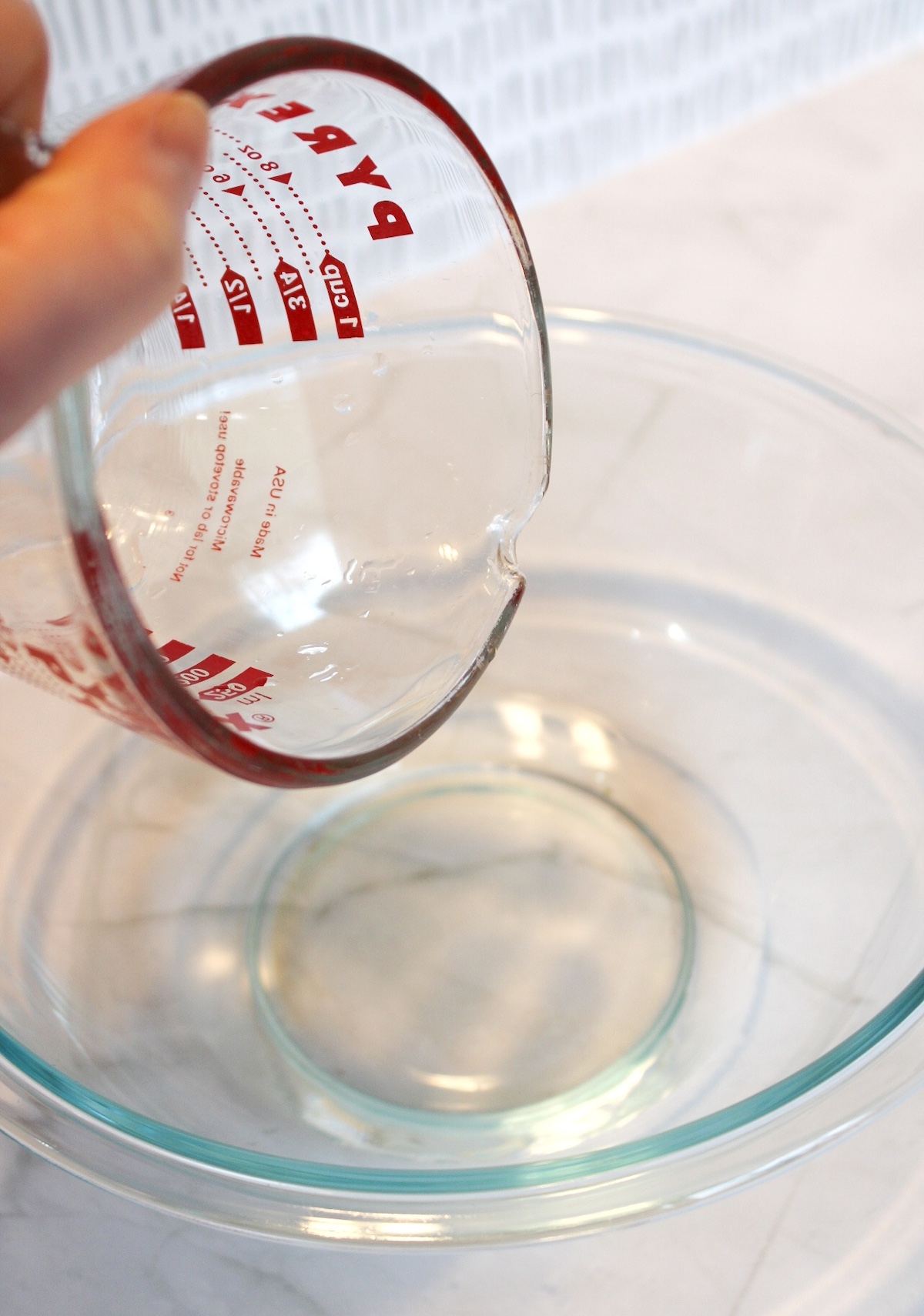 pouring water into a clear glass bowl