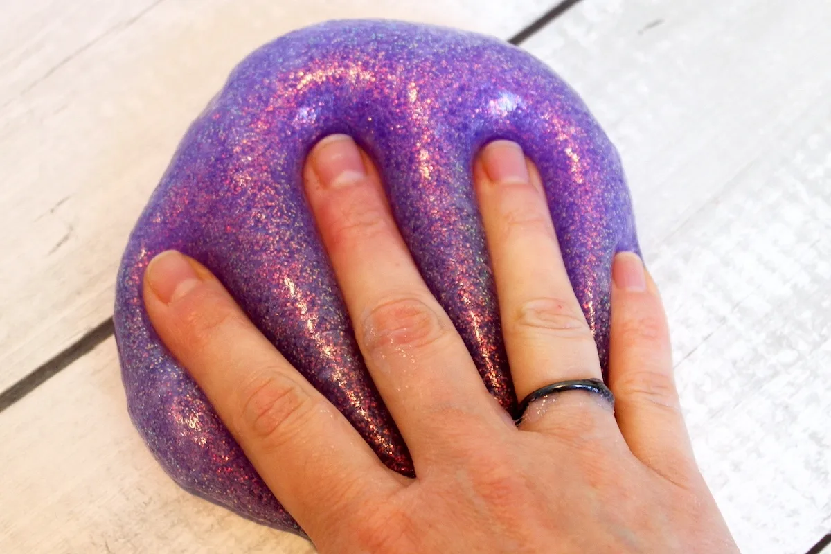 woman's hand pressing slime and glitter