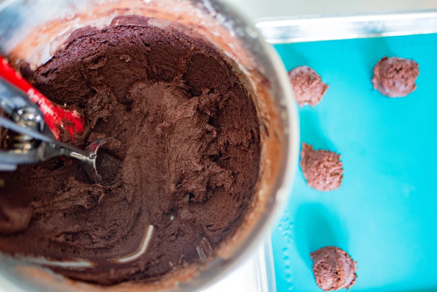 Dark chocolate cookie dough being scooped out of a metal bowl