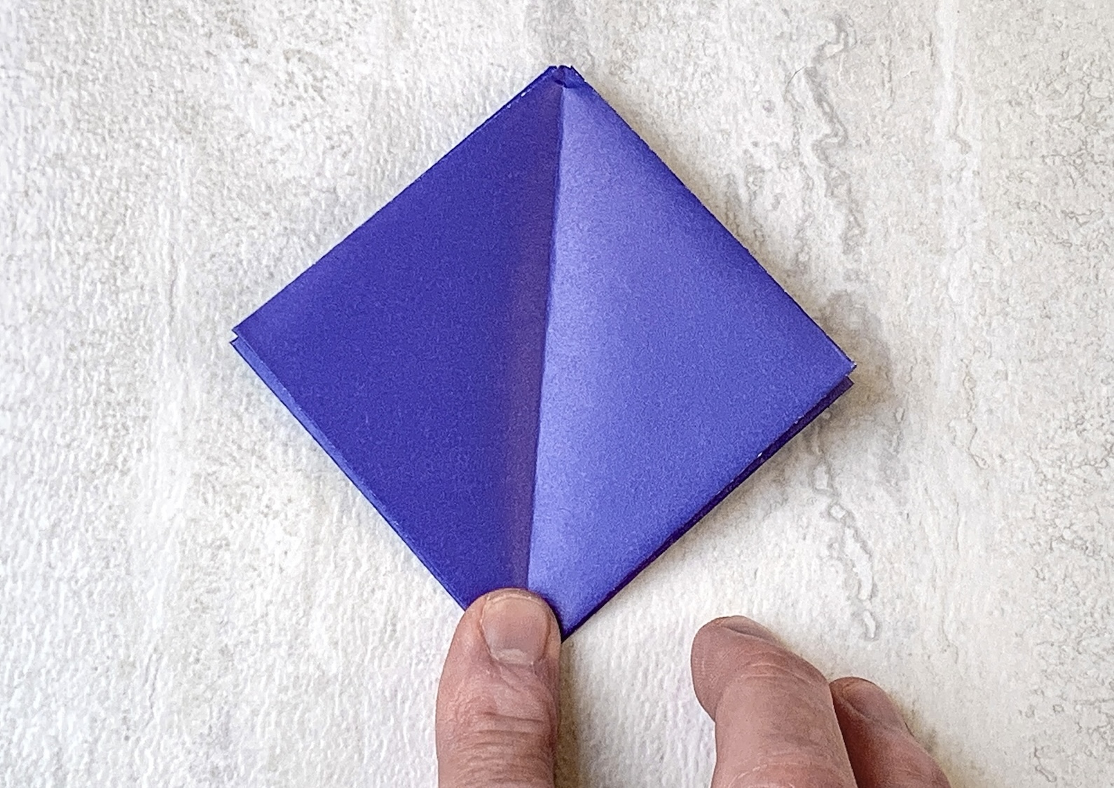 purple square of origami paper folded on a surface
