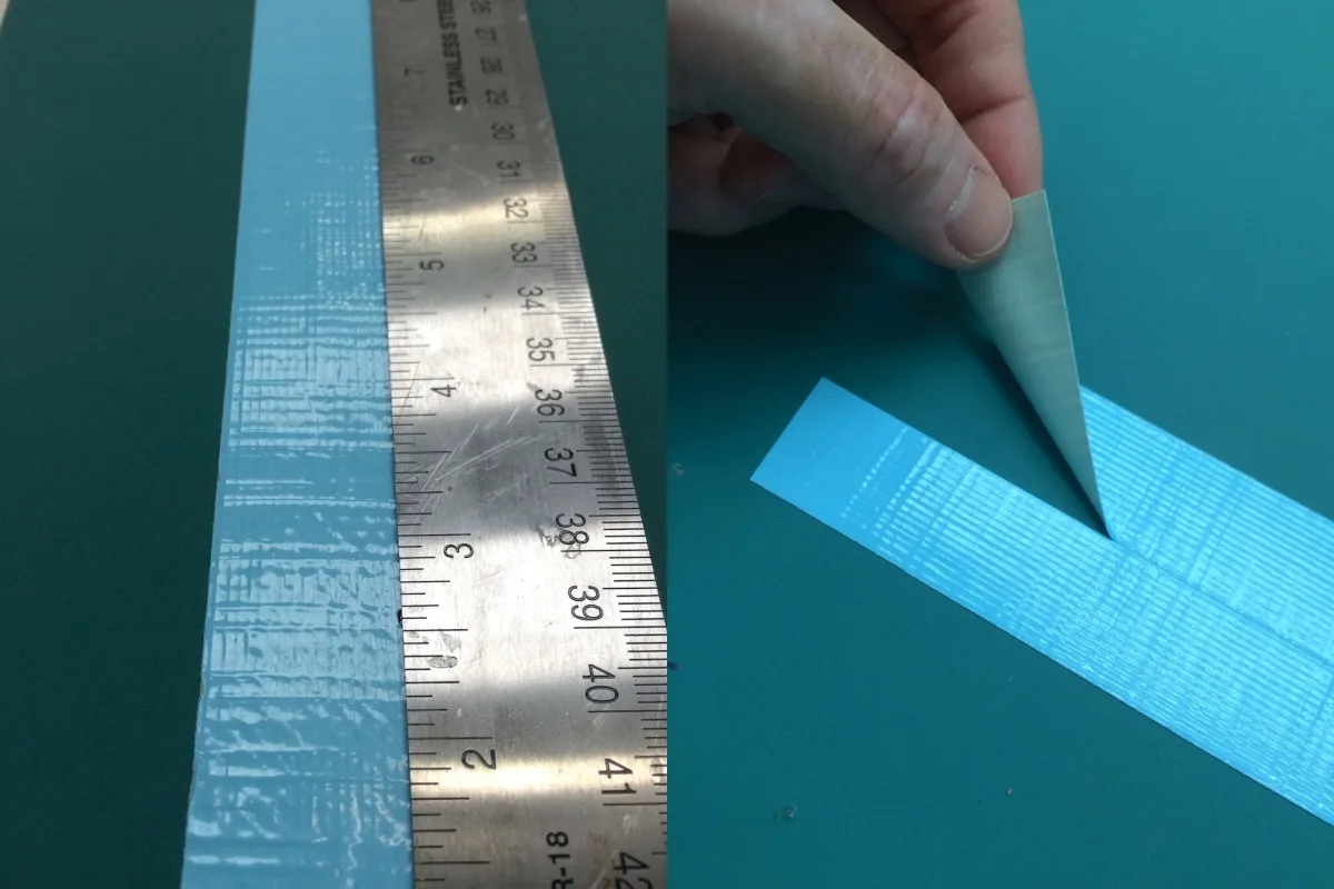 blue duck tape cut in half with a craft knife using a ruler